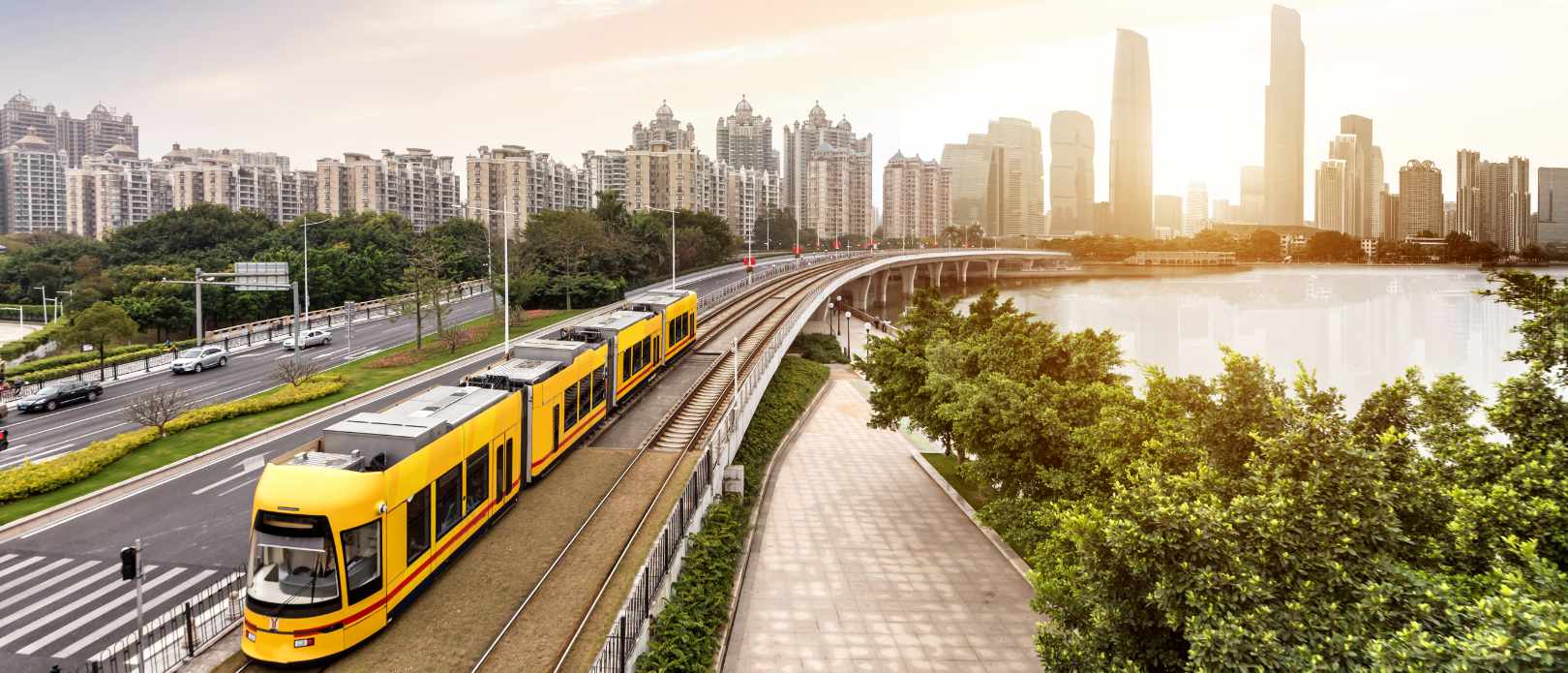 Picture of yellow train with city high buildings and lake in the background