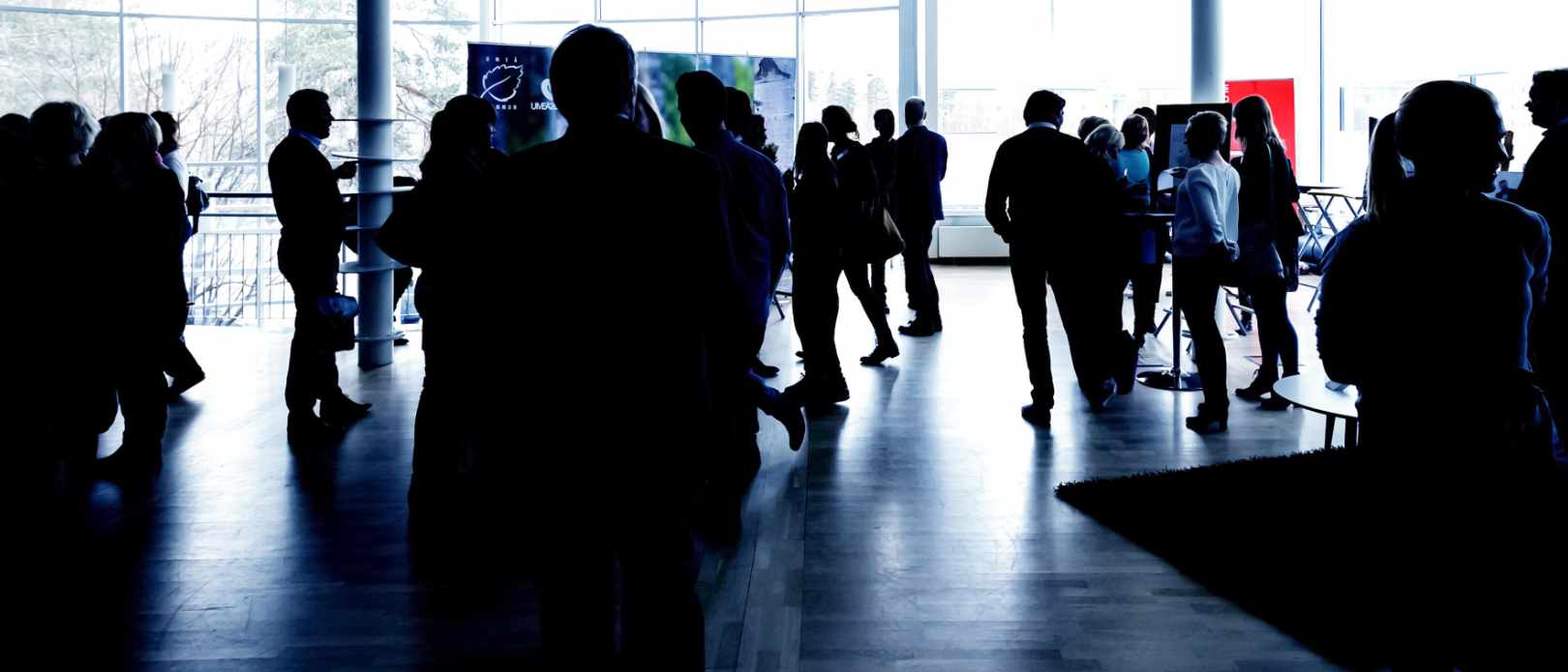 Silhouettes of people talk during an event