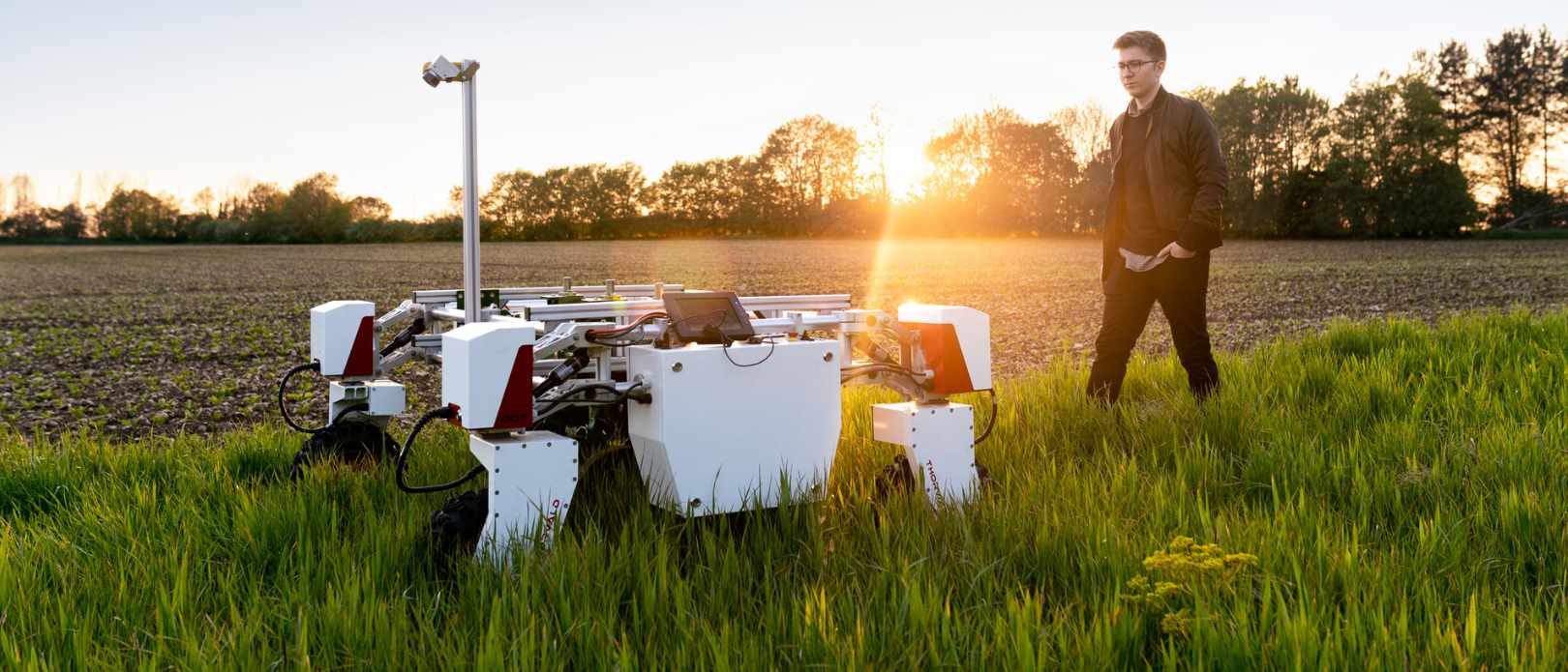 Man standing with sustainable agricultural robot in field
