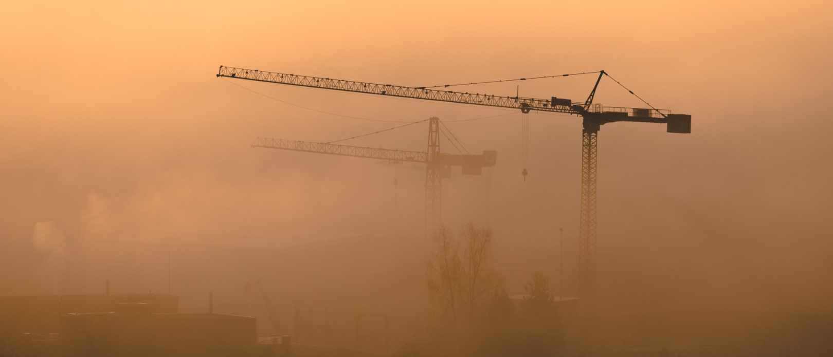 Two cranes seen through smog